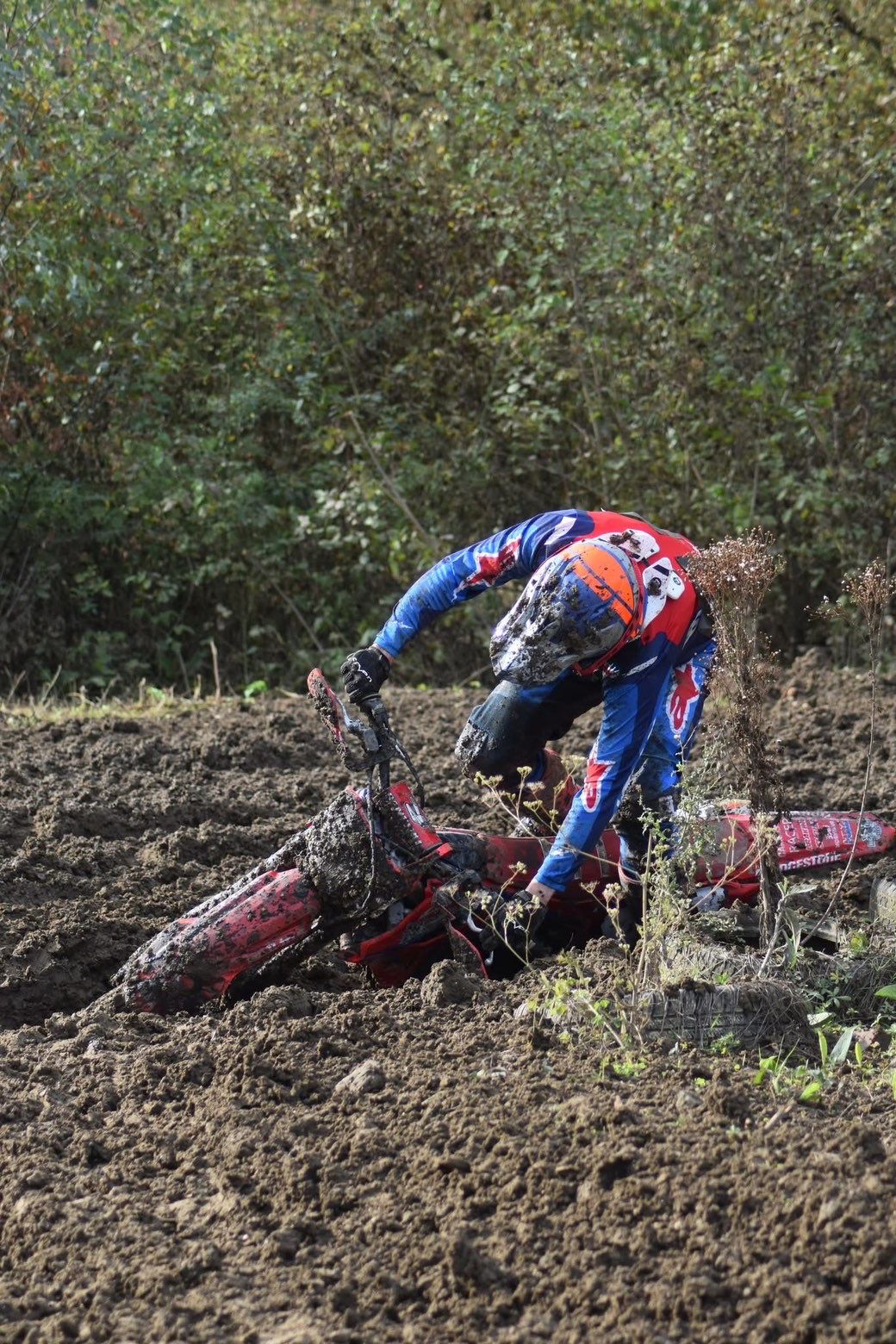 Baptiste redressant sa Honda rouge enlisée en bord de piste